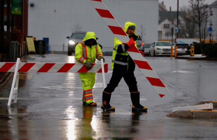 City workers erect barriers to keep traffic out of a flooded Somerset Street in Portland's Bayside neighborhood on December 21, 2018. Heavy rains, a storm surge and an astronomical high tide combined to flood several low-lying streets in the city Friday morning.