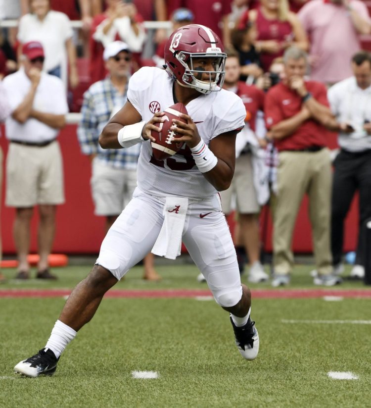 FILE - In this Oct. 6, 2018, file photo, Alabama quarterback Tua Tagovailoa rolls out before throwing a touchdown pass on the first play of the game against Arkansas in the first half of an NCAA college football game, in Fayetteville, Ark. Tagovailoa is the offensive player of the year and one of five members of the top-ranked Crimson Tide to earn first-team honors on The Associated Press All-Southeastern Conference team, announced Monday, Dec. 3, 2018. Tagovailoa, one of the prime contenders for the Heisman Trophy, has thrown 37 touchdown passes with only four interceptions to rank second nationally in passing efficiency. (AP Photo/Michael Woods, File)