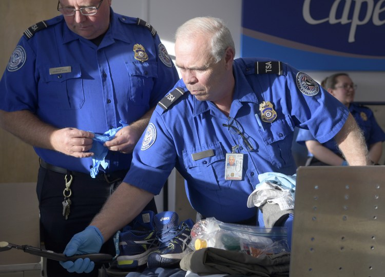 Transportation Security Administration screeners examine luggage Monday at the Augusta State Airport. The federal employees are deemed essential, but they have been working without pay since Dec. 22, when the federal government was shut down.