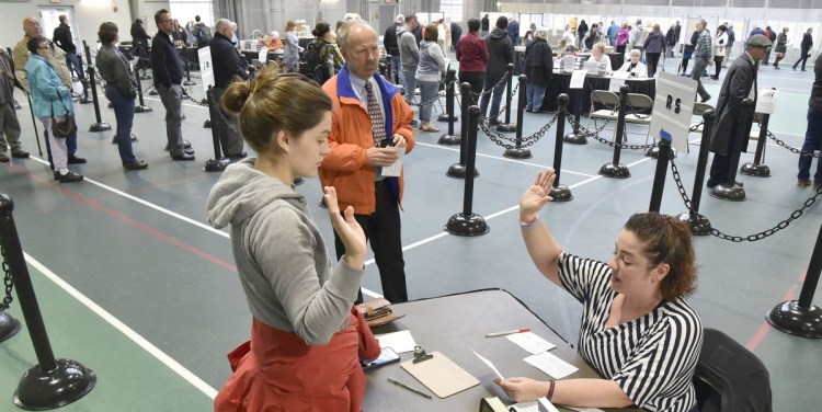 Colby College student Alexandria Fraize, left, swears the information she gave election clerk Allison Brochu is accurate before voting at Thomas College on Nov. 6, 2018. City Solicitor Bill Lee observes.
