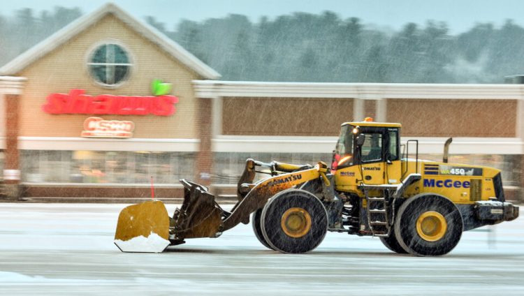 A front-end loader clears the parking lot around 7:15 a.m. Wednesday at Shaw's Plaza in Augusta.