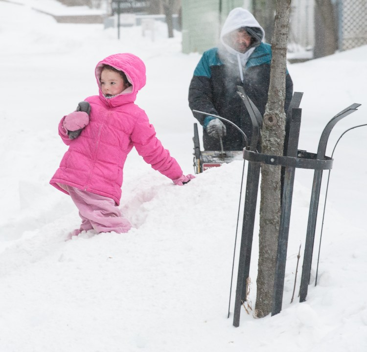 Olivia Reil tries to climb a snowbank as her grandfather snowblows on Horton Street in Lewiston during Sunday's Nor'Easter. (Sun Journal photo by Russ Dillingham)