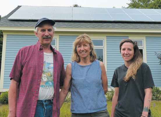 From left, Jake Plante, Marcia Harrington and Alexandra Plante stand in front of the solar panels mounted on the garage at their Rossmore Road home in Brunswick. The solar panels were assessed by the town and taxed as real property, a decision Plante, Harrington and six other property owners with solar panels are seeking to have overturned.