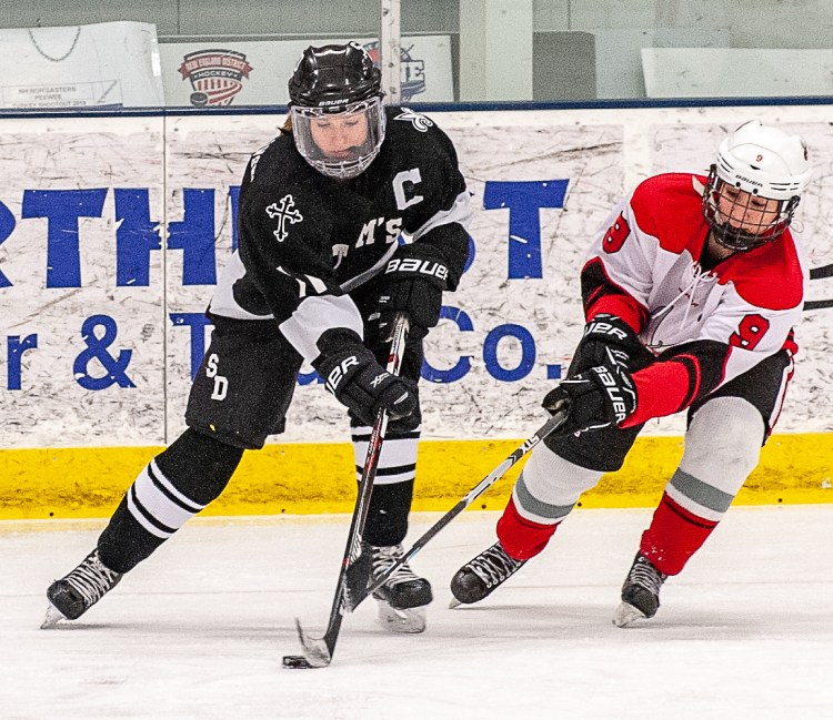 Saint Dominic Academy's Avery Lutrzykowski, left, and Red Hornets' Taylor Cailler battle for the puck earlier this month in Auburn.