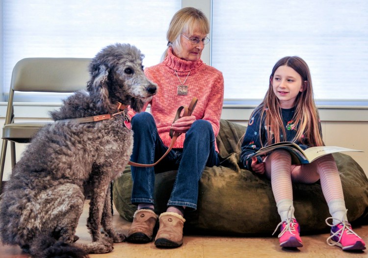 Lily the labradoodle, left, and Gail Balch listen as Sophie Moore reads them a book aloud Thursday at Isaac F. Umberhine Public Library in Richmond.