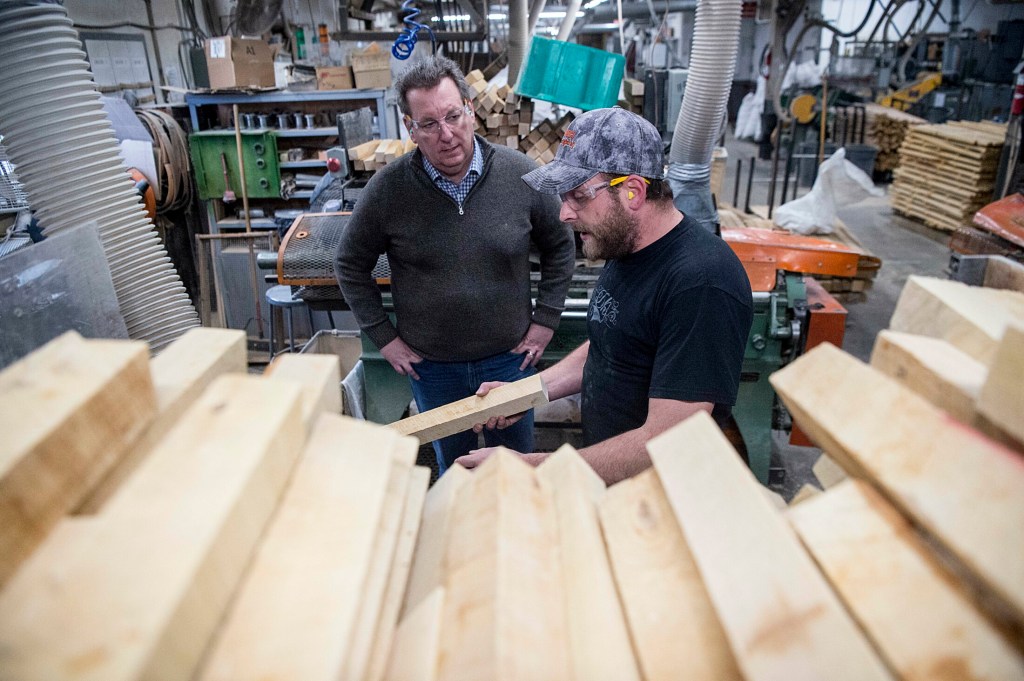 Nick Fletcher, right foreground, talks on Friday with Michael Conway, director of sales and marketing at Maine Wood Concepts in New Vineyard while checking out blocks of wood that will soon be transformed into Easter eggs.