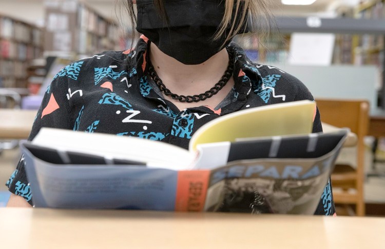 A student wears a mask while reading Thursday in the Edward Little High School library in Auburn.