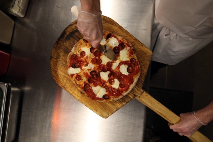 Mike LaRubio, sous chef at Monte's Fine Foods on outer Washington Avenue in Portland, slices pepperoni pizza. 