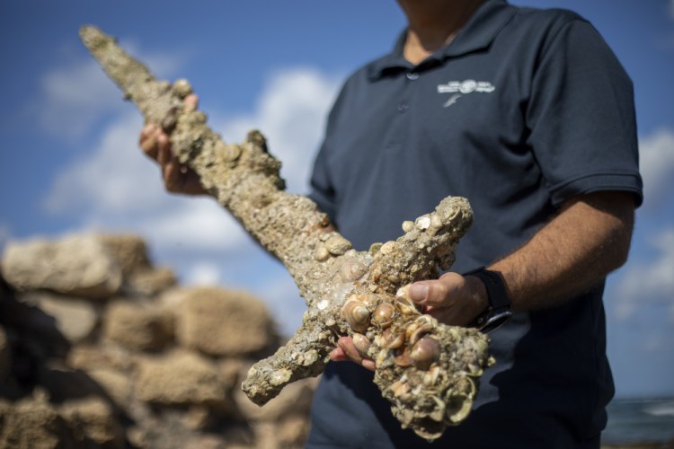 Jacob Sharvit, director of the Marine Archaeology Unit of the Israel Antiquities Authority. holds a yard-long sword that experts say dates back to the Crusaders, in Mediterranean seaport of Cesarea, Israel, on Tuesday. 