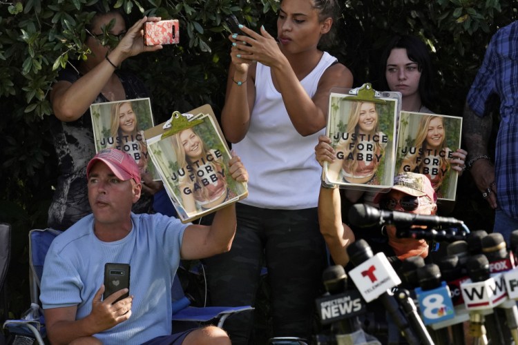 Supporters of Gabby Petito hold up photos of her after a news conference Wednesday in North Port, Fla., following the discovery of remains that have been identified as those of Brian Laundrie, who had been sought in Petito's killing. 