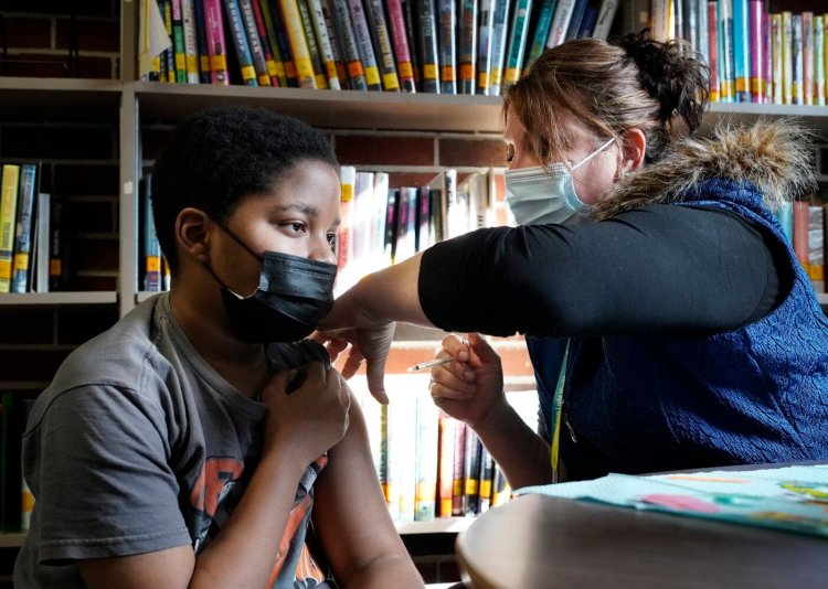 Ali Maguire, a paramedic with Northern Light Health, administers a Pfizer vaccine to Hassani Broadus, a sixth-grader at Memorial Middle School, during a clinic at the South Portland school on Friday.