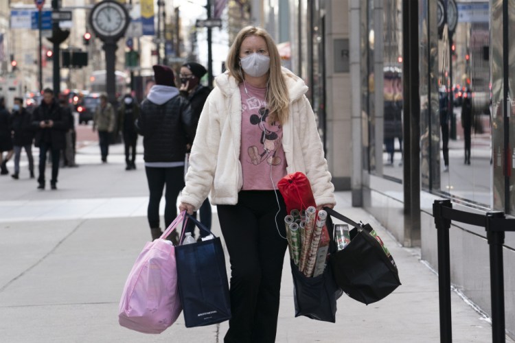A woman carries shopping bags in New York in December 2020.  The National Retail Federation expects that holiday sales gains could shatter last year’s record-breaking season even as a snarled global supply chain slows the flow of goods and results in higher prices for a broad range of items. 