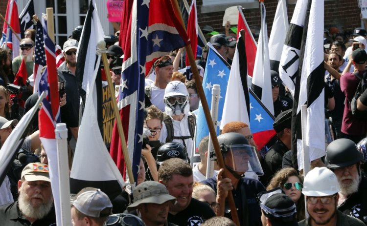 White nationalist demonstrators walk into the entrance of Lee Park surrounded by counter demonstrators in Charlottesville, Va., on Aug. 12, 2017. 