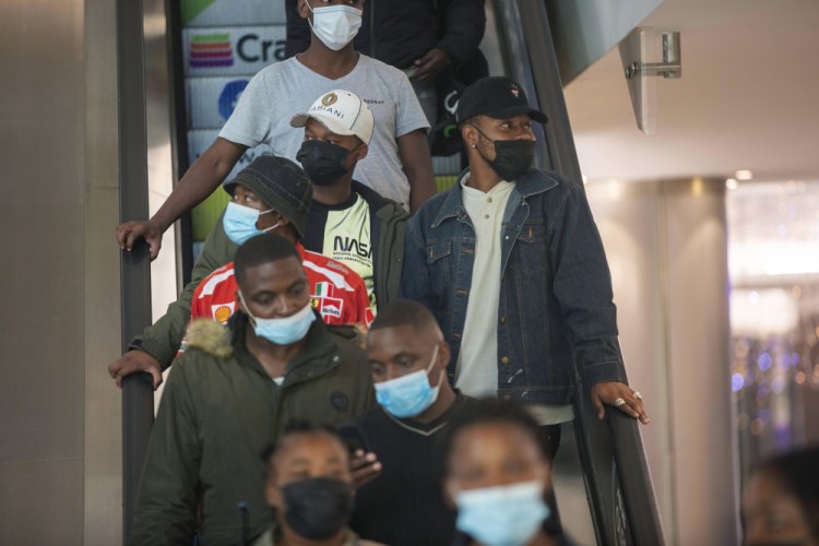 People wearing masks on an escalator at a shopping mall, in Johannesburg, South Africa, Friday Nov. 26, 2021. 
