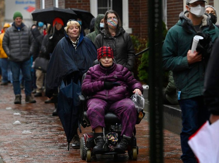 Kathleen Kuefler, 73, of Portland sits while waiting in line with others for the Community Vaccination Clinic at Mechanics Hall on Saturday in Portland.