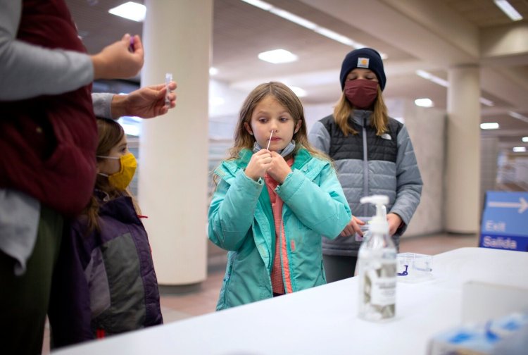 The rapid PCR COVID-19 testing site at Portland International Jetport is available to passengers and the general public and being administered by Curative. Lucy Cameron, 8, of Portland self-administers a nasal swab while mom and sisters Maeve, 6, left, and Natalie look on. 