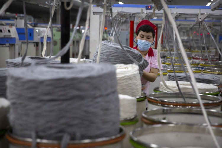 A worker gathers cotton yarn at a textile manufacturing plant in Aksu in western China's Xinjiang Uyghur Autonomous Region in April.