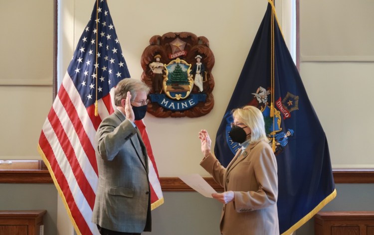 Gov. Janet Mills swears in William Harwood as Maine's new public advocate on Wednesday in Augusta.
