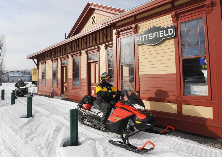 Snowmobilers pass the historic Pittsfield depot building in Pittsfield earlier this month. Snowmobile clubs in central Maine say inconsistent temperatures and rainfall have hampered this winter's riding season.