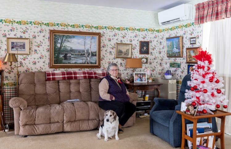 Pam Partridge at her home in North Anson on Wednesday. Partridge said the price of her oil heat went up 40 cents per gallon last month. She also has a heat pump, pictured in the upper right corner, and often uses her wood-burning stove in the kitchen in the mornings to help keep the room warm.