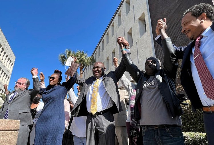 The family and attorneys of Ahmaud Arbery raise their arms in victory outside the federal courthouse in Brunswick, Ga., on Tuesday after all three men involved in his killing were found guilty of hate crimes.