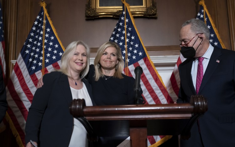 Former Fox News anchor Gretchen Carlson, center, celebrates with Sen. Kirsten Gillibrand, D-N.Y., left, and Senate Majority Leader Chuck Schumer, D-N.Y., after Congress gave final approval to legislation guaranteeing that people who experience sexual harassment at work can seek recourse in the courts, at the Capitol in Washington, Thursday, Feb. 10, 2022. 