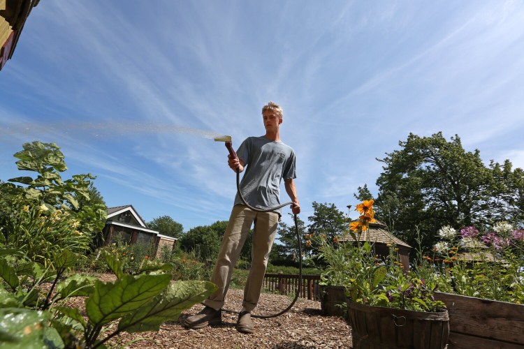 CAPE ELIZABETH, ME - JULY 31: Aidan Connor, an employee at Jordan Farm in Cape Elizabeth, waters plants outside the farm's market on Sunday. "It's been really hot and the sun has just been blaring down," he said. (Staff photo by Ben McCanna/Staff Photographer)