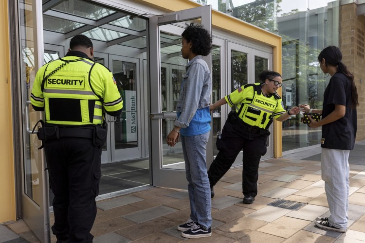 Security guards check identification for proof of age outside the Mall in Columbia, Friday, May 12, 2023, in Columbia, Md. The mall has implemented a "Parental Guidance Required" program, which requires that all visitors under 18 be accompanied by an adult who is at least 21 after 4 p.m. on Fridays and Saturdays. 