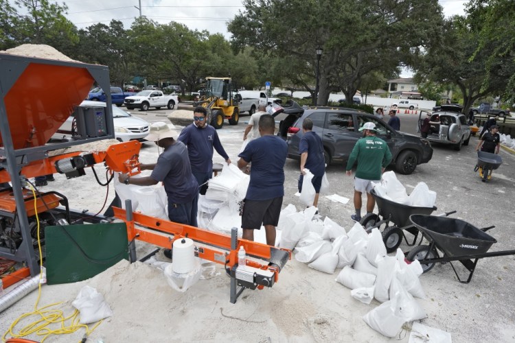 Members of the Tampa, Fla., Parks and Recreation Department help residents with sandbags Monday. Residents along Florida's Gulf Coast are making preparations for the effects of Tropical Storm Idalia. Chris O'Meara/Associated Press