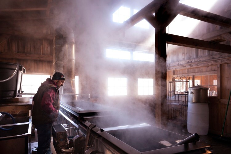Keith Harris checks on maple sap boiling in an evaporator in a sugarhouse at Harris Farm in Dayton.